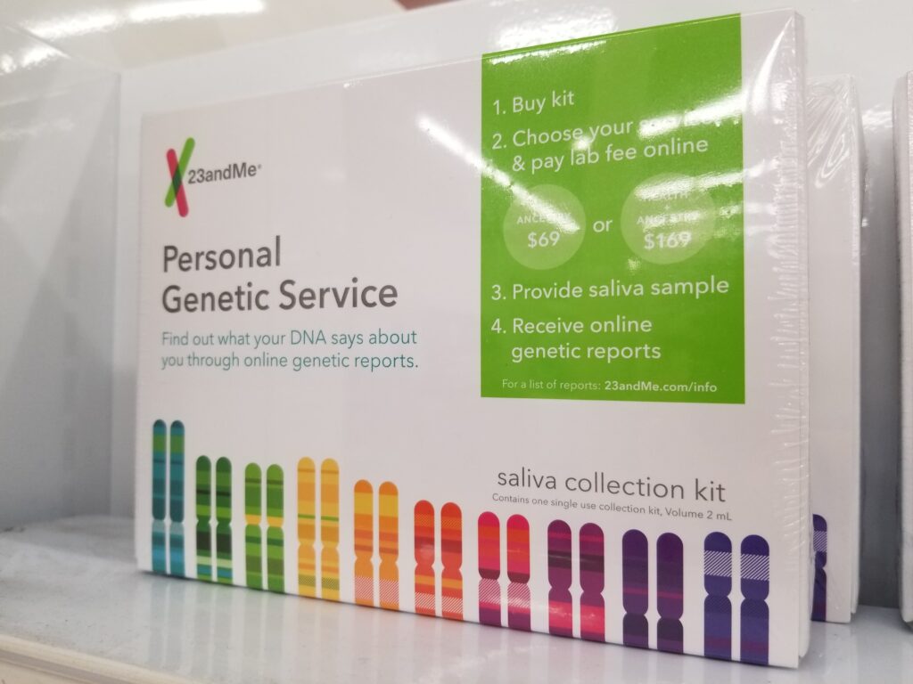 Uma caixa branca com as palavras “Serviço Genético Pessoal” e representações gráficas coloridas de genes está em uma prateleira.